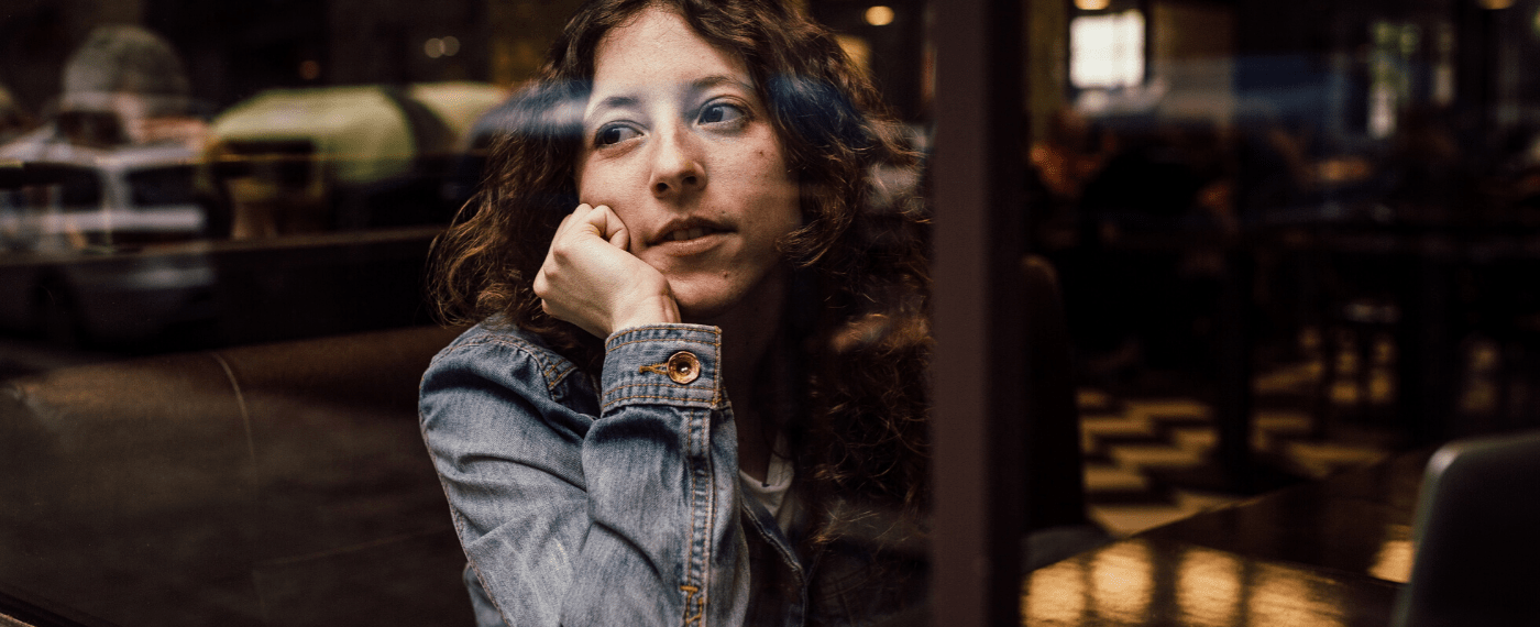 Woman staring out of restaurant window thinking about old songs