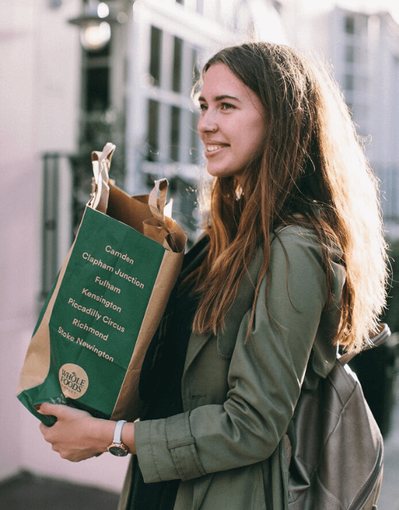 woman smiling while carrying recyclable bag of groceries