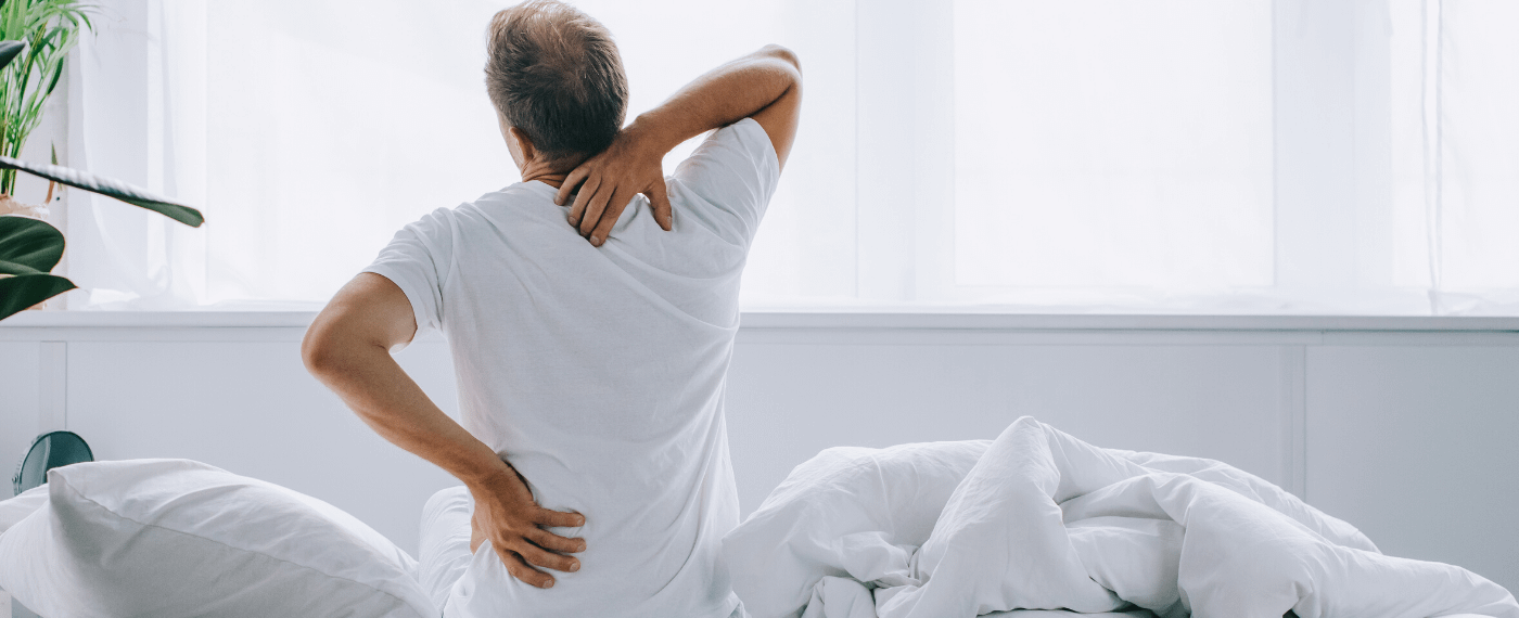 Man waking up fro sleep stretching back in a painful manner